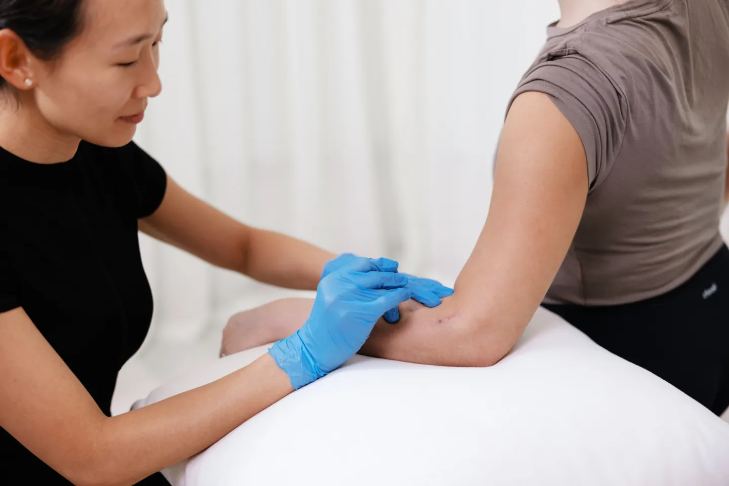 A Goji physiotherapist using dry needling on a client's forearm during a session.
