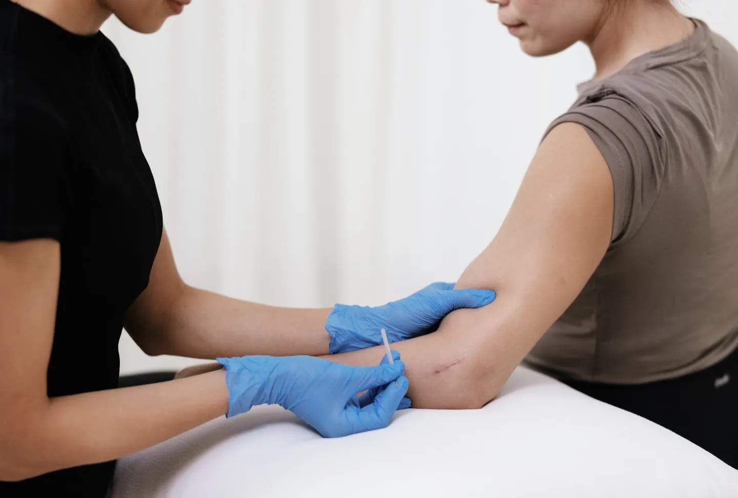 A Goji physiotherapist applying dry needling to a client's forearm.