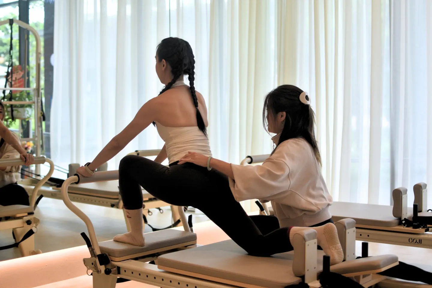A Pilates instructor guiding a client through a reformer lunge during a Private Pilates session at Goji.
